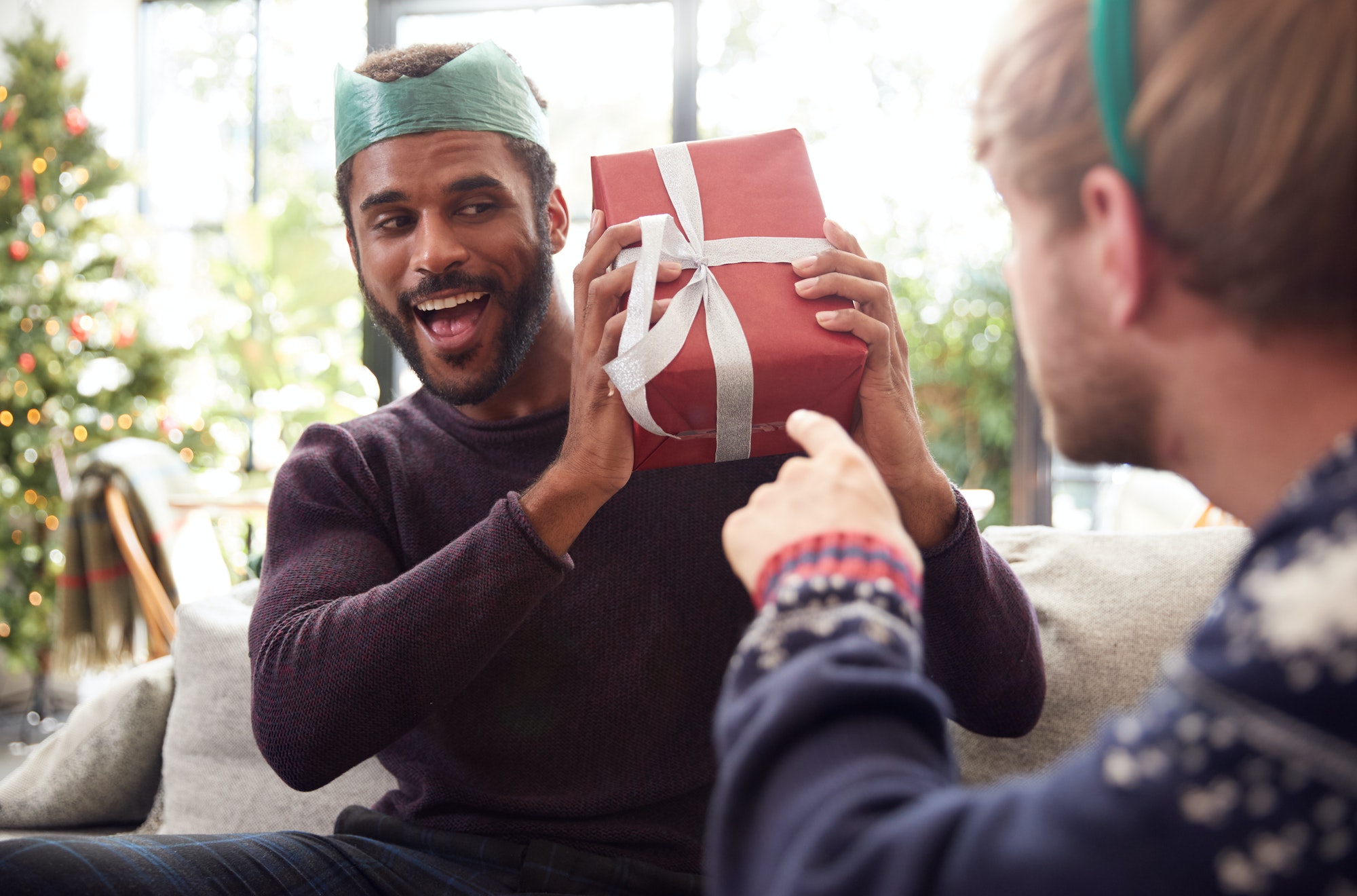 Gay Male Couple At Home Exchanging Gifts On Christmas Day Together