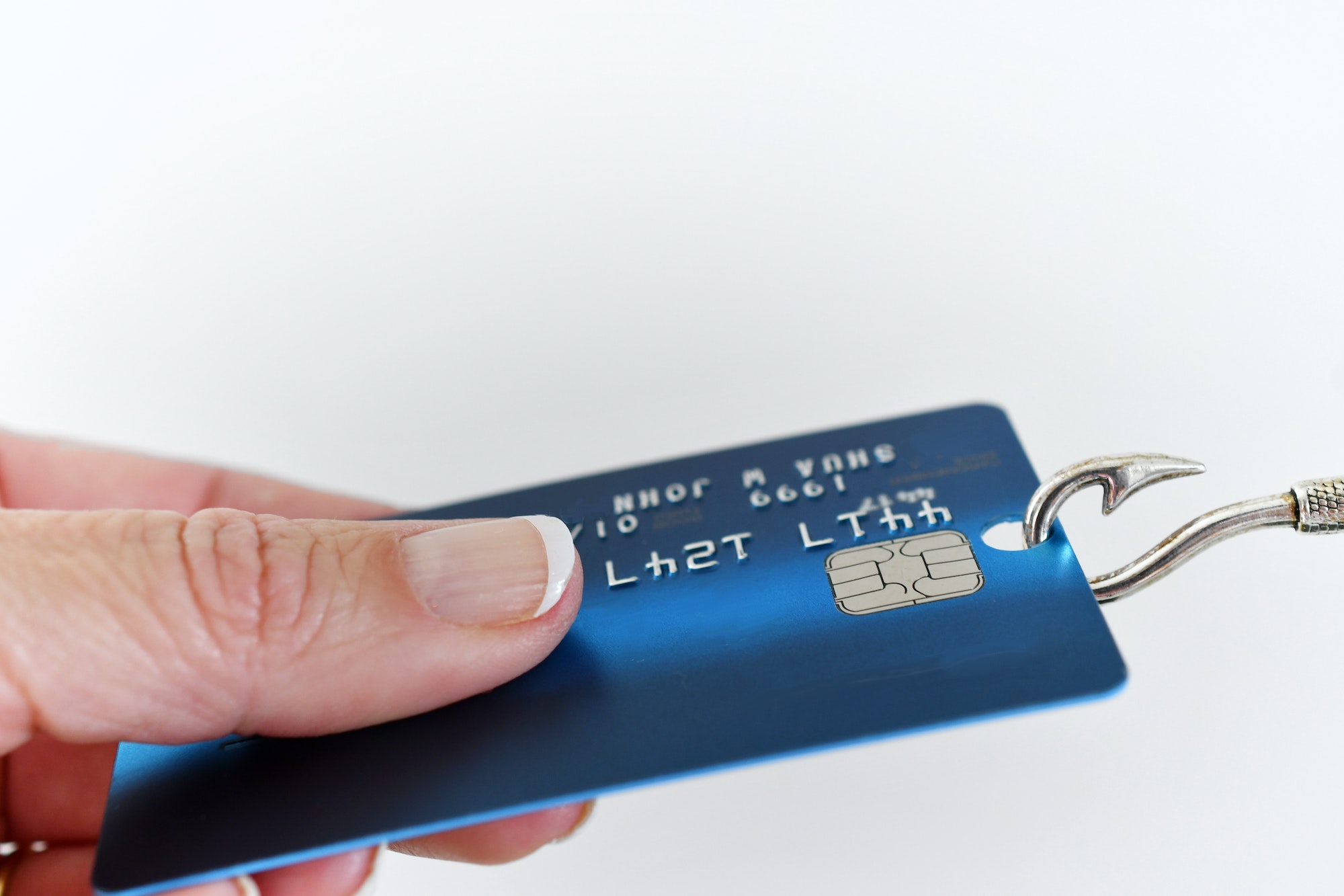 Phishing scam fraud identity theft concept - hand holding onto credit card on fishing hook